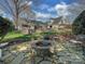 Landscaped backyard with stone patio, fire pit, and multiple seating areas for outdoor entertaining at 2326 Lathrop Ln, Charlotte, NC 28211