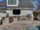 Outdoor kitchen with stone accents, granite counters, stainless grill, and a TV for entertaining by the pool at 2326 Lathrop Ln, Charlotte, NC 28211