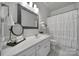 This bathroom has a single vanity, a decorative mirror, and a tub-shower combination with a white shower curtain at 2399 Woodridge Dr, Fort Mill, SC 29715