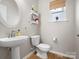 Stylish powder room with a pedestal sink, decorative shelves, and a window at 421 Silver Cypress Ln, Fort Mill, SC 29708