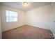 Cozy bedroom with neutral carpet, one window for natural light, standard ceiling light, and door to hallway at 4910 Lailwood Cir, Charlotte, NC 28227