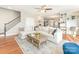 Open-concept living room features hardwood floors, a large sofa, and a staircase in a naturally lit space at 620 Briar Patch Ter, Waxhaw, NC 28173