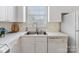 Close-up kitchen view with stainless steel sink, dishwasher, and white cabinets at 8759 Coralbell Ln, Charlotte, NC 28213