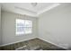 Bright bedroom with wood-look flooring, a tray ceiling, and a window with blinds at 1008 Beaugard Dr, Charlotte, NC 28208