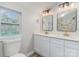 Bright bathroom with double sinks, a toilet, and a tiled shower visible in the mirror at 102 S Liberty St, Gastonia, NC 28052