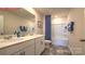 Bathroom with double vanity, a bath tub with a blue shower curtain and gray tile floors at 107 Windstone Common Ln, Mooresville, NC 28117