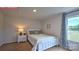 Bright bedroom featuring carpet flooring, a large window with patterned curtains, a full bed and a bedside table at 107 Windstone Common Ln, Mooresville, NC 28117