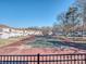 Community tennis court surrounded by trees and nearby residential buildings on a sunny day at 10901 Carmel Crossing Rd, Charlotte, NC 28226