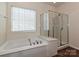 Bathroom featuring a soaking tub beneath a window and a separate glass-enclosed shower at 14309 Stonewater Ct, Fort Mill, SC 29707