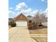 Charming single-story brick home featuring a two-car garage and a well-manicured front yard with blooming tree at 14309 Stonewater Ct, Fort Mill, SC 29707