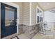 Cozy front porch with stone accents, a dark blue front door, and rocking chairs to relax in at 1660 Sassafras Ct, Fort Mill, SC 29715