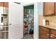 Pantry with organized shelving and wood cabinets adjacent to stainless steel refrigerator at 3960 Franklin Meadows Dr, Matthews, NC 28105