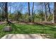 Spacious backyard with a lush green lawn, mature trees, and a concrete patio at 6212 Windsor Gate Ln, Charlotte, NC 28215