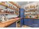 Custom home bar featuring blue cabinets, wood countertops, wine fridge, and ample shelving for storage at 7034 Pin Oaks Dr, Denver, NC 28037