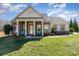 Inviting home with stone-accented porch columns, blue chairs and lush green lawn at 7034 Pin Oaks Dr, Denver, NC 28037