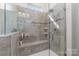 The tile shower features glass door, built in bench, shower head and soap and shampoo niches at 7034 Pin Oaks Dr, Denver, NC 28037