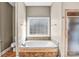 Bathroom featuring a soaking tub with tile surround, decorative accents, and a frosted window at 8005 Bridger Pt, Waxhaw, NC 28173