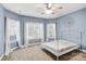 Blue bedroom featuring a ceiling fan, three windows, and white metal frame bed at 8005 Bridger Pt, Waxhaw, NC 28173