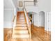 Entryway with hardwood floors, wooden stairs, white accents, and a view to the living room fireplace at 8005 Bridger Pt, Waxhaw, NC 28173