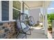 Cozy front porch featuring stylish outdoor seating with decorative pillows and a charming stone accent wall at 9843 Quercus Ln, Huntersville, NC 28078