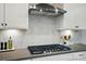 Close-up of a kitchen featuring a stainless steel range hood over a gas cooktop and a white marble backsplash at 9843 Quercus Ln, Huntersville, NC 28078