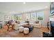 An open concept living room featuring a white sectional sofa, large windows, and modern decor, creating a bright and airy space at 9843 Quercus Ln, Huntersville, NC 28078