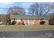 Charming single-story brick home featuring a well-maintained lawn, front porch and mature trees at 1060 Laurel Ln, Gastonia, NC 28054