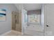 This bright bathroom has a soaking tub, walk-in shower with glass door and a window at 114 Runningdeer Dr, Mooresville, NC 28117