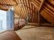 An attic area featuring exposed wooden beams, door, and insulation, indicating potential for storage or renovation at 2411 Calais Pl, Charlotte, NC 28211