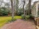 Serene backyard with a brick patio, lush greenery, and mature trees creating a private outdoor oasis at 2411 Calais Pl, Charlotte, NC 28211