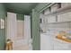 The bathroom showcases a tiled shower-tub, washer and dryer with overhead shelving, and sage green walls at 2500 Cranbrook Ln # 2, Charlotte, NC 28207