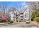 Exterior view of condos featuring a grey exterior, balconies, a parking lot and mature trees at 2500 Cranbrook Ln # 2, Charlotte, NC 28207