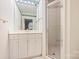 White bathroom featuring a shower with glass doors, a single sink vanity and an inset mirror at 318 S Canterbury Rd, Charlotte, NC 28211