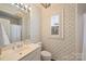 Small bathroom features a single sink vanity, toilet, and shower/tub combo with patterned wallpaper at 318 S Canterbury Rd, Charlotte, NC 28211