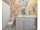 Bright bathroom featuring a tub/shower and floral wallpaper with a white single sink vanity at 318 S Canterbury Rd, Charlotte, NC 28211