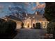 Elegant, light pink home featuring a circular driveway and well-manicured landscaping at dusk at 318 S Canterbury Rd, Charlotte, NC 28211