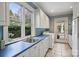 Bright laundry room with a blue counter, white cabinetry, and a large window offering a lush outdoor view at 318 S Canterbury Rd, Charlotte, NC 28211