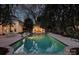 Twilight view of a stunning swimming pool and patio area, surrounded by trees and the home's illuminated exterior at 318 S Canterbury Rd, Charlotte, NC 28211