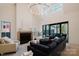 Bright living room with a fireplace, high ceilings, modern chandelier, and a dark-colored couch at 412 Bertonley Ave, Charlotte, NC 28211