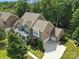 An aerial view showcasing a brick home with a three car garage surrounded by lush trees and greenery at 4708 Pearmain Dr, Waxhaw, NC 28173