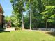 Lush backyard features a well-maintained lawn, mature trees, a brick patio, and a deck with stairs at 4708 Pearmain Dr, Waxhaw, NC 28173