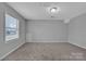 A bright bedroom featuring a window that provides exterior light and neutral walls and carpet at 49 Orchard Trace Ct, Taylorsville, NC 28681