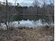 Beautiful still pond surrounded by trees, reflecting the sky, at the edge of this expansive property at 4926 Stack Rd, Monroe, NC 28112