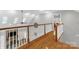 Upstairs hallway with hardwood floors, white railings, and views of the stone fireplace below at 507 Saint Johns Dr, Salisbury, NC 28144