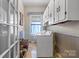 Bright laundry room featuring a washer, dryer, storage cabinets, and a window with blue curtains at 524 W Horah St, Salisbury, NC 28144