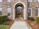 Close-up of arched front door framed by white pillars and brick, complemented by manicured bushes at 5501 Two Iron Dr, Matthews, NC 28104