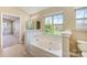 Bright bathroom features a soaking tub with tile surround, tiled floor and large window at 6720 Neuhoff Ln, Charlotte, NC 28269