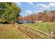 A scenic view of a pond with a fountain, surrounded by a lush green lawn and a rustic split rail fence at 6720 Neuhoff Ln, Charlotte, NC 28269