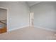 A well lit bedroom with neutral colors and carpet, leading to an ensuite bathroom and staircase at 810 Martingale Ln, Davidson, NC 28036