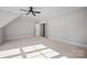 Sunlit attic bedroom featuring neutral carpet, ceiling fan, and ensuite bathroom at 810 Martingale Ln, Davidson, NC 28036